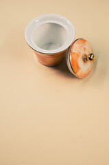 Sticker - Close up of an orange empty cup next to a cover on an orange isolated background with free space