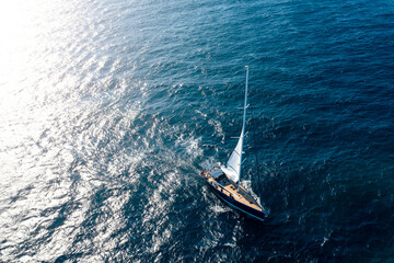 Wall Mural - View from above, stunning aerial view of a sailboat sailing on a blue water at sunset. Costa Smeralda, Sardinia, Italy.