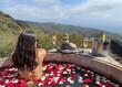 Beautiful woman relaxing and celebrating life in a jacuzzi full of petals with oceanfront view