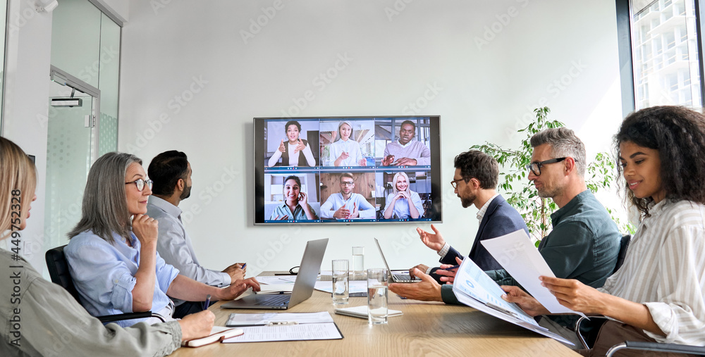 Diverse company employees having online business conference video call on tv screen monitor in board meeting room. Videoconference presentation, global virtual group corporate training concept. - obrazy, fototapety, plakaty 
