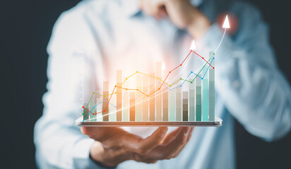 Businessman holding tablet bar graph of analytics and financial, Changes in new planning, Business growth, ideas and perspectives, Stock investment, and dividends yield from business in the new year