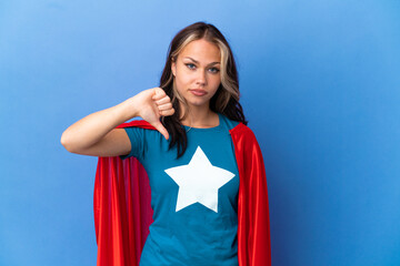 Wall Mural - Super Hero Teenager girl isolated on blue background showing thumb down with negative expression