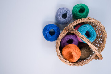 Poster - Pile of colorful textile balls of wool in a wicker basket on blue background with a copy space