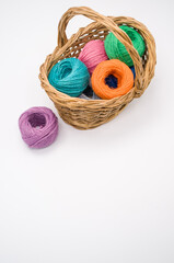 Poster - Pile of colorful textile balls of wool in a wicker basket on white background with a copy space