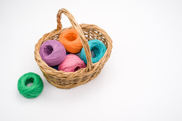 Sticker - Pile of colorful textile balls of wool in a wicker basket on white background with a copy space