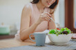 © interstid - Cropped shot of happy woman eating fresh vegetable salad in white bowl in kitchen.  enjoying a healthy food