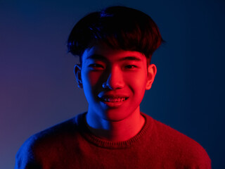 Wall Mural - Color light people. Synth wave portrait. Split personality. 80s sci-fi style. Smiling Asian man face in bright colorful red blue neon glow isolated on dark background.