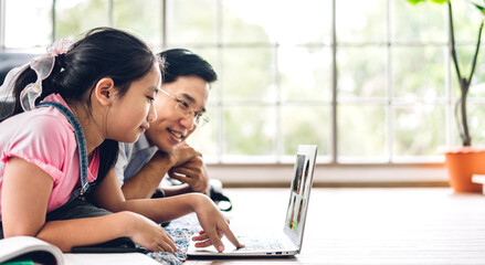 Father and asian kid little girl learning and looking at laptop computer making homework studying knowledge with online education e-learning system.children video conference with teacher tutor