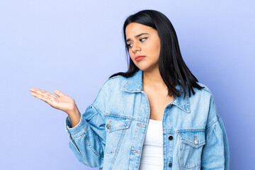 Wall Mural - Young latin woman woman over isolated background holding copyspace with doubts