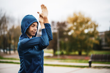 Wall Mural - Adult woman is exercising outdoor on cloudy day in autumn.