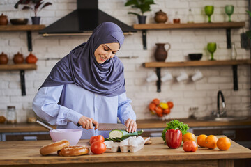 Wall Mural - Young Arabian woman cutting a zucchini and smiling