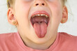 Cheerful child. Girl laughs close-up of the face on a white background. A little girl show tongue throat. portrait with wide open mouth and protruding tongue. with clear view pulls out long tongue