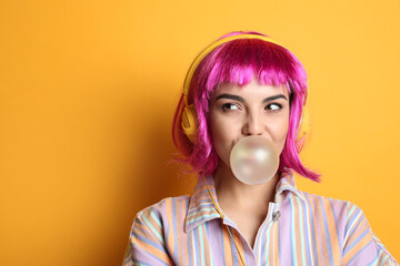 Sticker - Fashionable young woman in colorful wig with headphones blowing bubblegum on yellow background, space for text