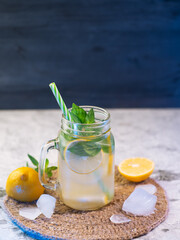 Wall Mural - Icy summer lemon mojito on a stone table with blue lighting . Detox water with lemon and mint