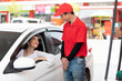 young woman in the car, talking to worker for refueling gasoline at the gas station