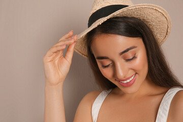 Canvas Print - Beautiful young woman wearing straw hat on beige background. Stylish headdress