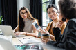 © LIGHTFIELD STUDIOS - smiling asian businesswoman pointing at cellphone with blank screen near interracial colleagues