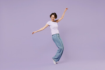 Full length side view young smiling excited cheerful happy woman 20s with bob haircut in white t-shirt leaning back stand on toes dancing have fun isolated on pastel purple background studio portrait.