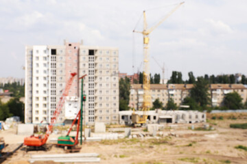 blurred view of construction site with heavy machinery near unfinished building