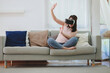 © interstid - Excited Asian woman using VR headset virtual reality at home in living room