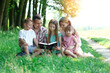 © Kostia - young family with children reading the Bible in nature