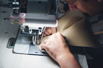 Wall Mural - Working process of leather craftsman. Tanner sews leather on a special sewing machine, close up.