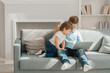 © yana_novak22 - Two little kids siblings seated on sofa in living room holding on lap laptop play online game, watch cartoons spend weekend using electronic device, bad habit, generation addicted with gadgets concept