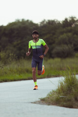 Wall Mural - Image of young professional male triathlete, runner in motion on open road. Concept of sport, lifestyle, activity.