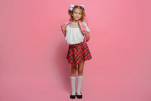 Elementary School Girl Carries A Backpack. Isolated On Pink Background