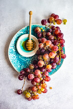 Overhead View Of A Bunch Of Red Grapes On A Plate With A Bowl Of Honey