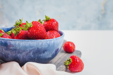 Wall Mural - Elegant tender strawberry background. Ripe summer red berries. Filled blue bowl or plate by seasonal strawberries. Sweet berry for morning breakfast