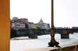 Beautiful metal leg of a lamppost. Ponte Santa Trinita is in the background. View from Ponte Vecchio. Florence, Italy.