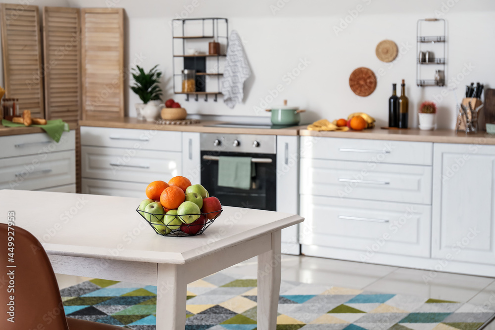 Basket with fresh fruits on dining table in kitchen