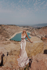 Wall Mural - beautiful woman with blond hair in elegant dress posing on the top of mountain with lake view