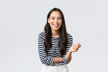 Wall Mural - Lifestyle, people emotions and casual concept. Carefree happy outgoing asian woman having fun talking to people, laughing and smiling upbeat, standing white background cheerful