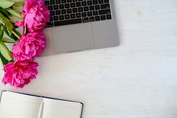 Wall Mural - Cropped shot or laptop computer keyboard, unfilled planning notebook and the bouquet of peony flowers with a lot of copy space for text on white table. Close up, top view, background.