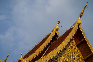 Canvas Print - Low angle shot of the red and golden roof of a temple in Thailand