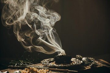 Charcoal burning with incense, incense resin, rosemary, laurel, lavender on a rustic wooden table, 
smudge stick, smudging, energetic cleansing and smoking.Sahumar
