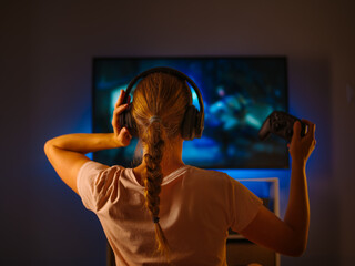 Wall Mural - Video game. The girl plays a video game with a joystick. Night time. Home furnishings. Day off. Hobby, gambling addiction. Gaming business. Color image.