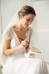 Poster - Young bride writing her single friends names on shoe indoors. Wedding superstition