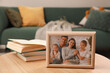 © New Africa - Framed family photo and books on wooden table indoors