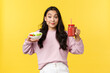 People emotions, healthy lifestyle and food concept. Silly and cute asian beautiful girl showing smoothie and vegan salad, smiling as trying stay on diet, standing yellow background