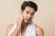© ME Image - Young Asian man applying moisturizer skin care cream on face after take a shower on brown background. Asian man with mustaches. Men's skin care.