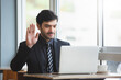 © eakgrungenerd - businessman raising hand to greet making video call on laptop. conference online. working new normal. Man working on computer laptop.
