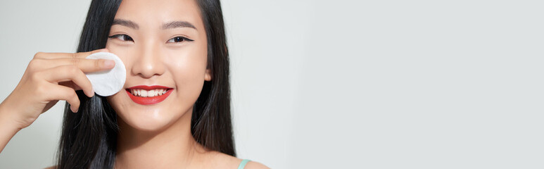 Wall Mural - Portrait of a young beautiful woman using sponge, isolated on a white background