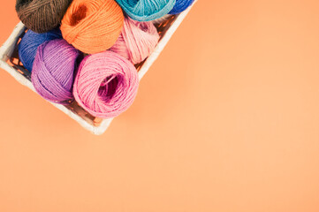 Wall Mural - Basket full of colorful yarn rolls isolated on an orange background with free space for text