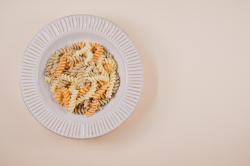 Wall Mural - Plate with pasta twists isolated on a beige background with free space for text