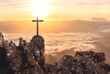 Silhouettes of crucifix symbol on top mountain with bright sunbeam on the morning mist sunrise background