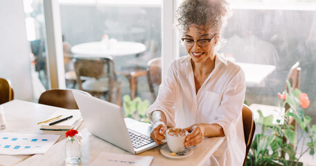 Wall Mural - Cheerful businesswoman having coffee in a cafe