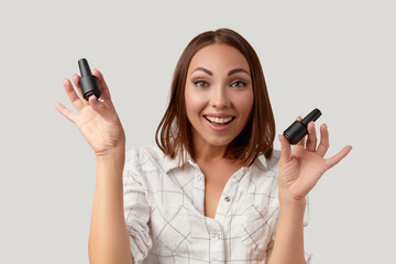 Wall Mural - Beautiful young woman excited and looking at camera holding bottles of nail varnish. Beauty portrait of brunette girl